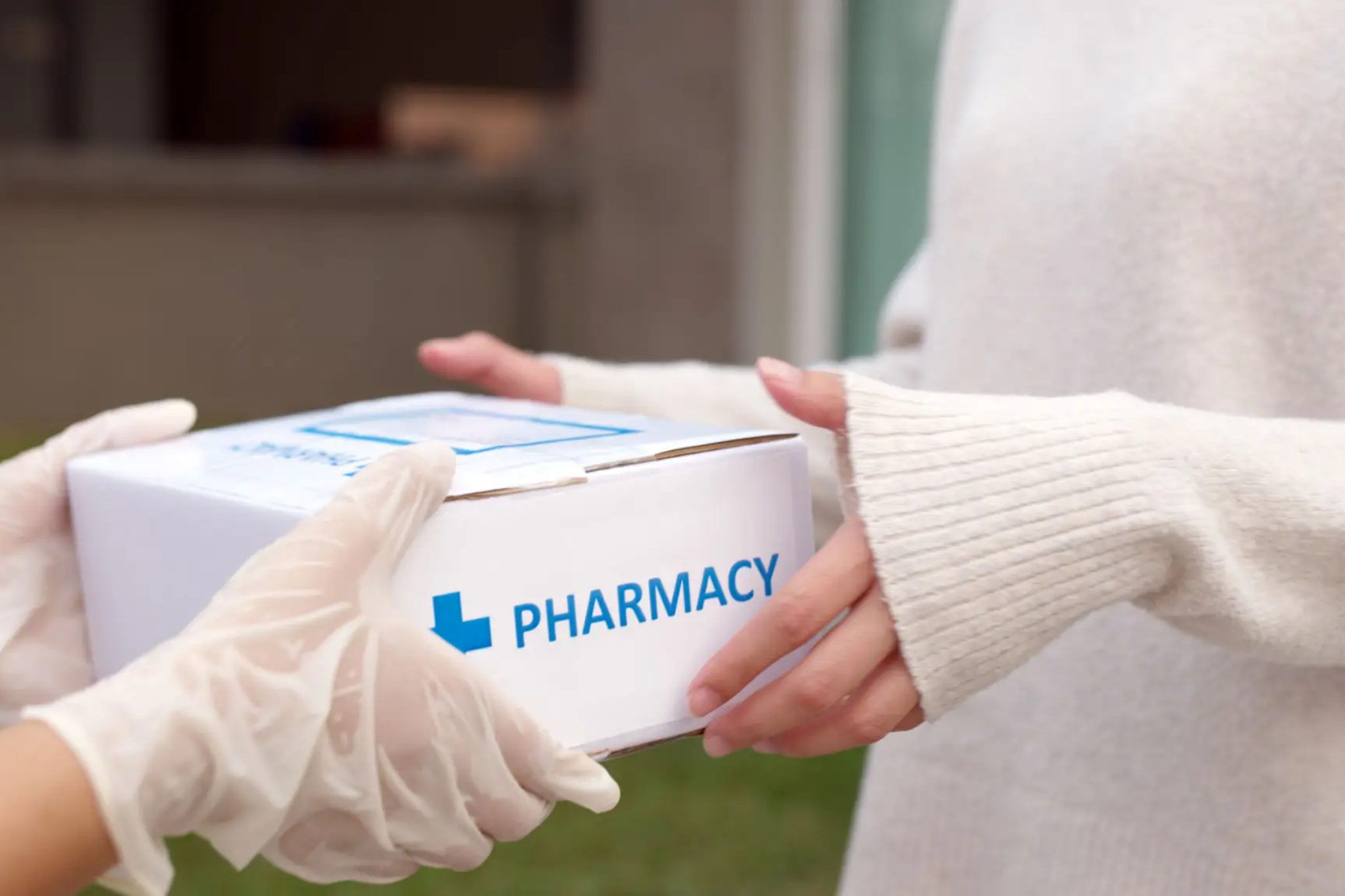 Hands exchanging a pharmacy delivery box.