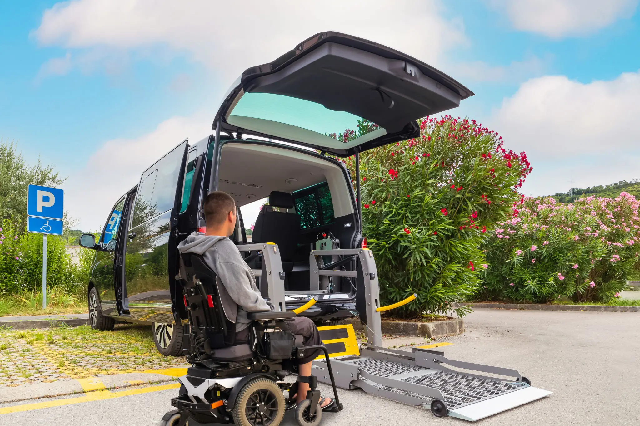Wheelchair user approaching accessible vehicle ramp.